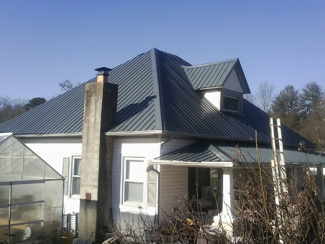 Dark blue standing seam metal roof on a white farmhouse with dormer — Slate & Tile Roof Repair by Roofing Brothers in Tucson