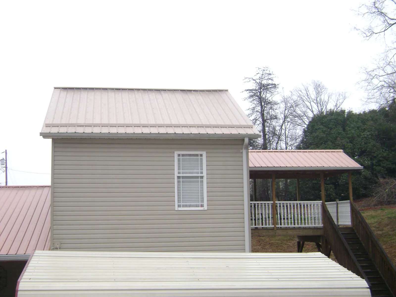 Tan metal roofs on a two story addition and attached porch, from a Roof Replacement job in Tucson