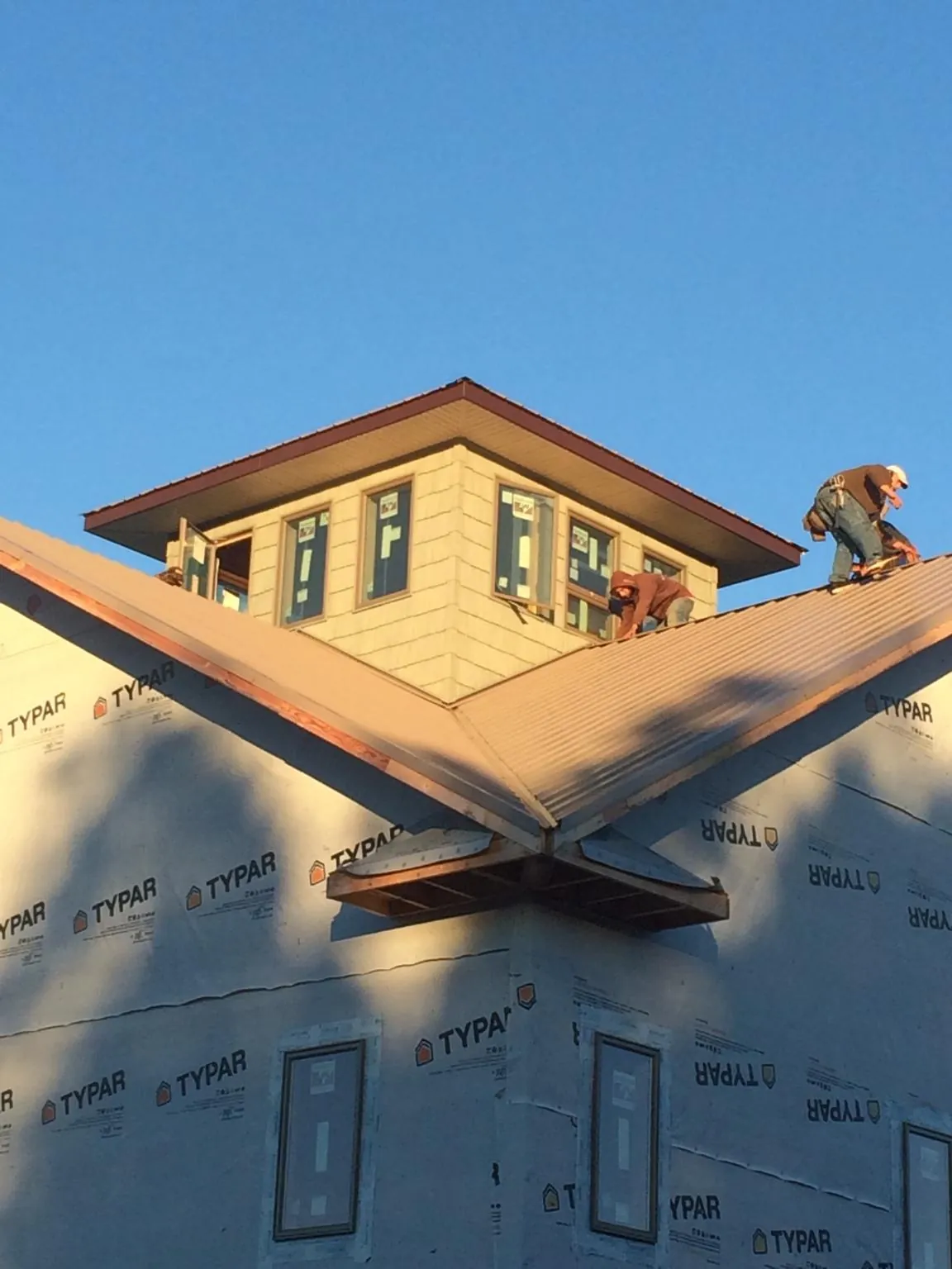 Roofers working around a rooftop cupola on a new metal roof at sunset — Roof Waterproofing in Tucson by Roofing Brothers